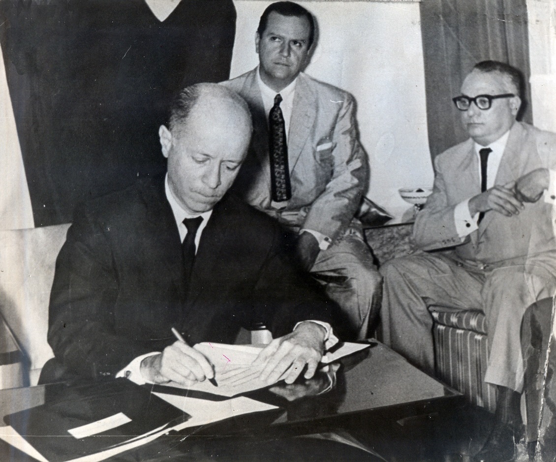 Jóvito Villalba firmando el documento que luego se conocería con el nombre de “Pacto de Punto Fijo”; observan Rafael Caldera y Rómulo Betancourt.